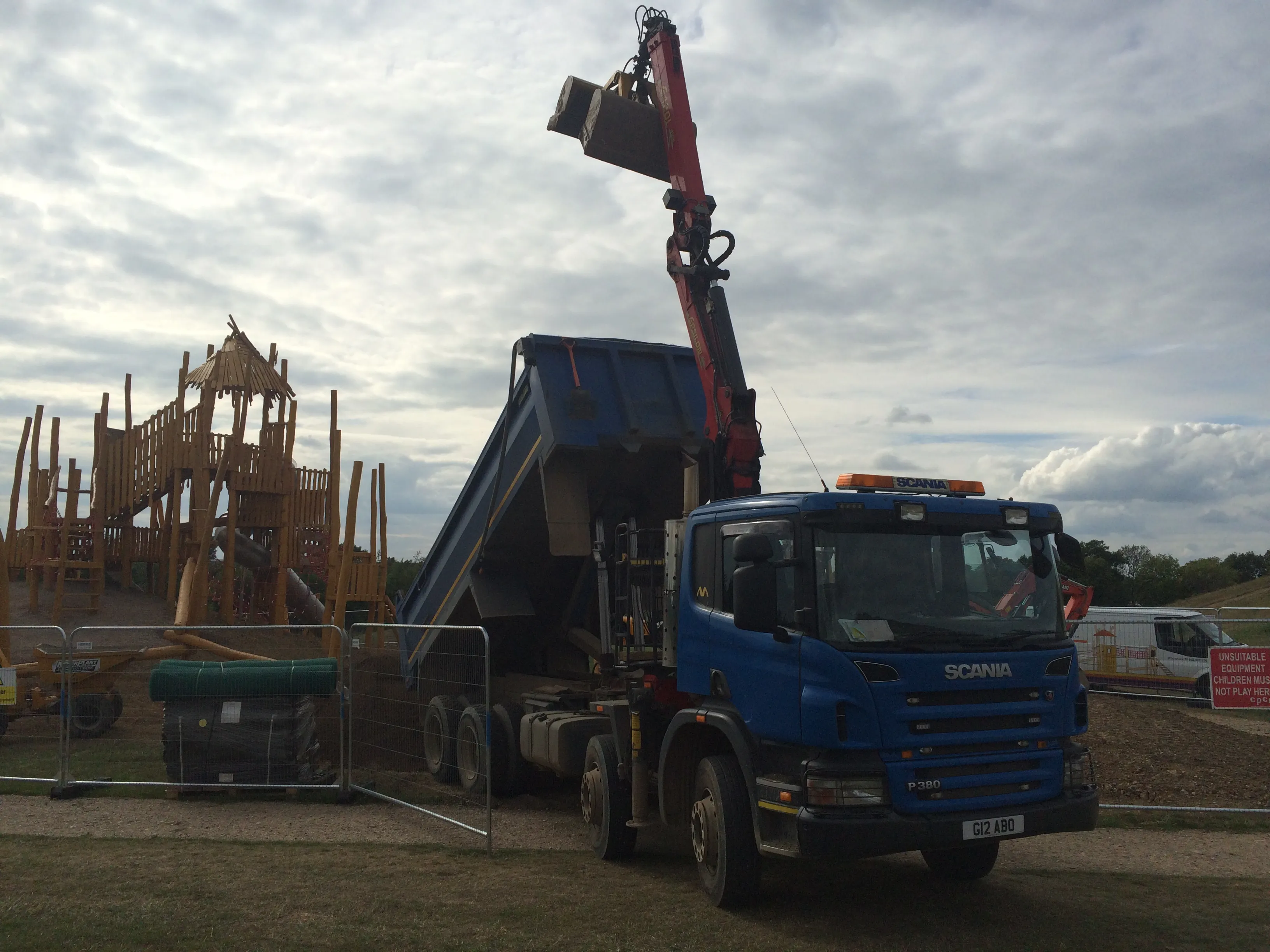 a blue dump truck parked next to a wooden structure